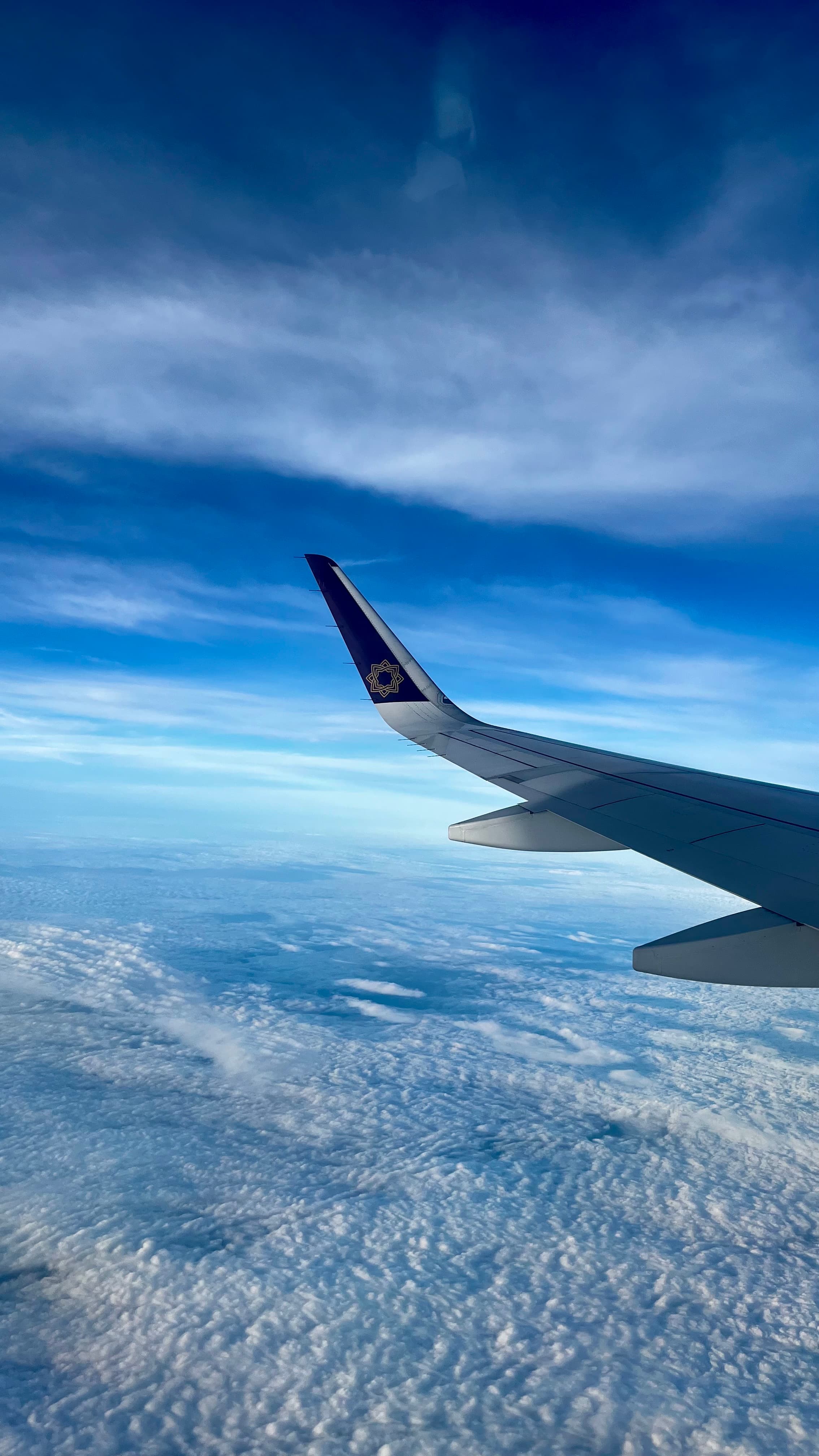 Airplane wing above a blanket of clouds during flight over India