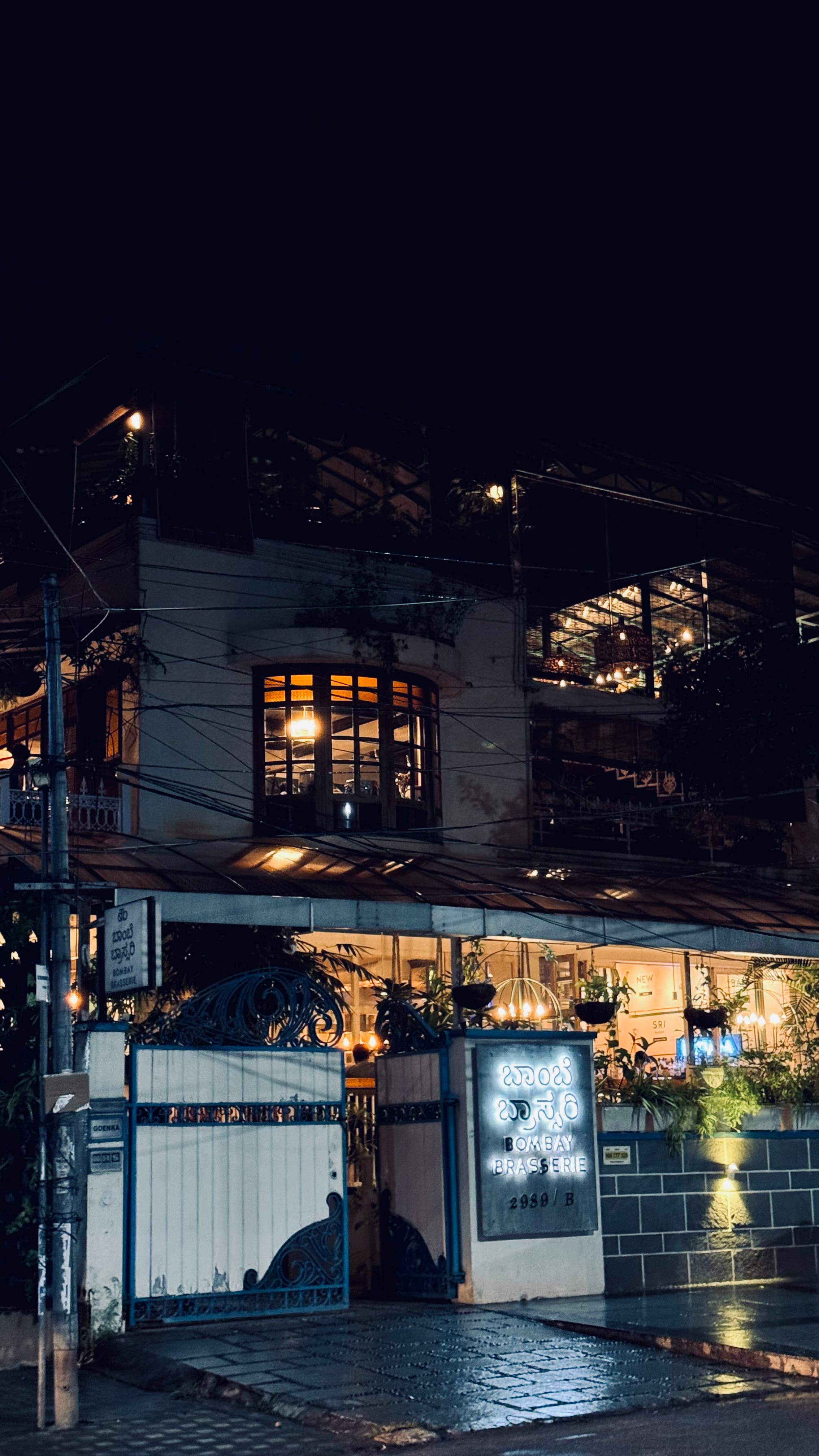 Restaurant facade lit warmly at night on a wet street in Bangalore