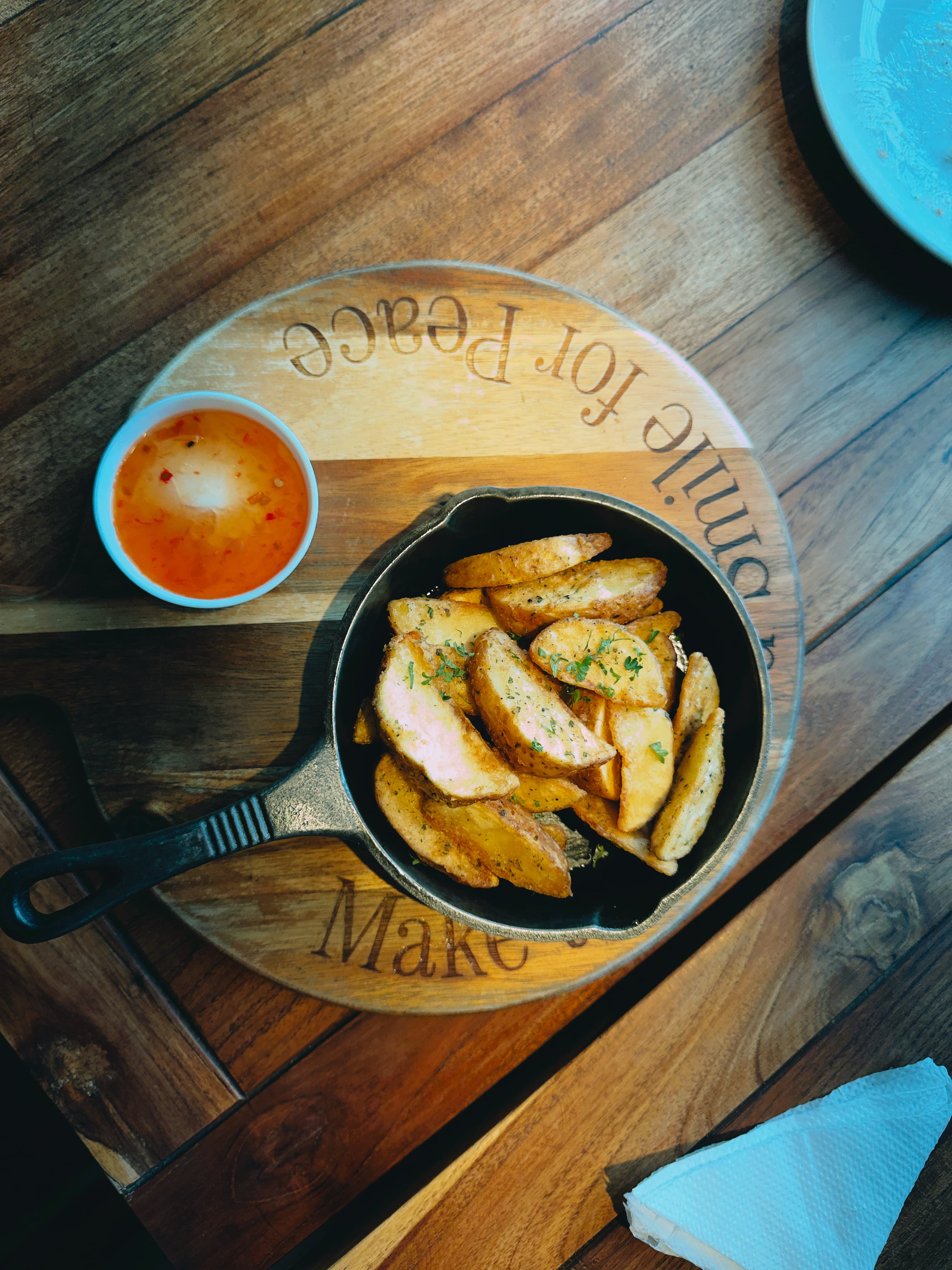Potato wedges in a cast iron skillet on a wooden board